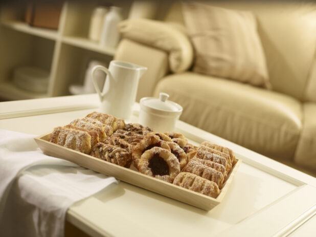 Mini pastry tray with assorted danishes on a rectangular wood catering tray on a coffee table in a living room setting
