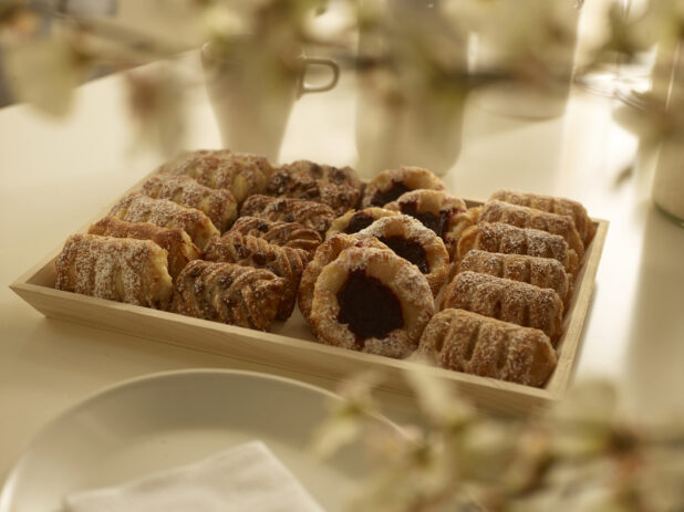 Assorted mini danish on a wood catering tray in a elegant table setting