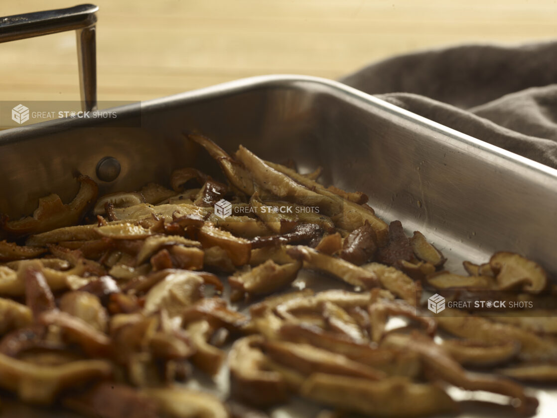 Sliced mushrooms in a roasting pan on a wooden background