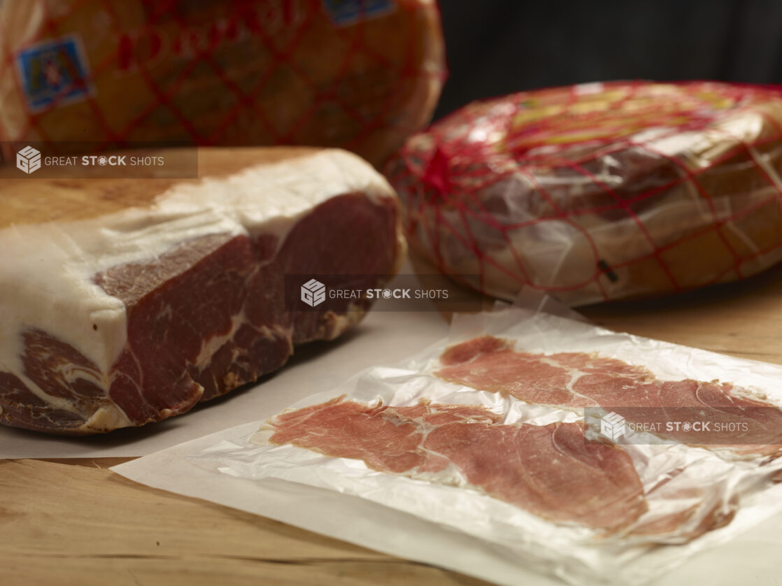 Whole and sliced prosciutto and Bayonne ham in a close up view on a wooden background