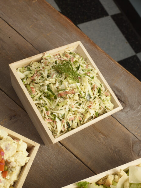 Coleslaw, potato salad, Caesar salad, in square wood catering boxes on a wooden background