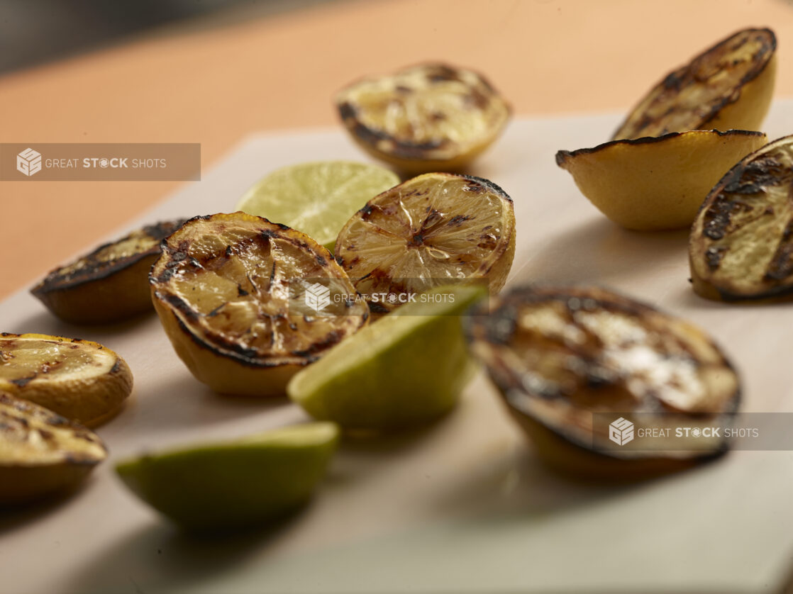 Close up view of grilled lemons and limes on a white foreground and a warm coloured background