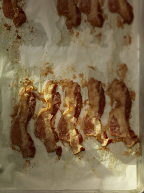Oven cooked bacon on parchment paper on a metal sheet tray