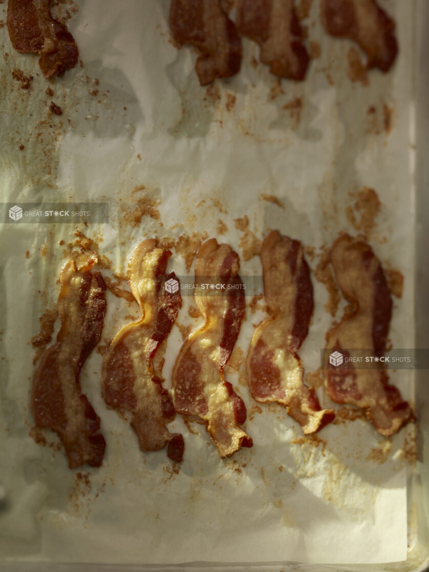 Oven cooked bacon on parchment paper on a metal sheet tray