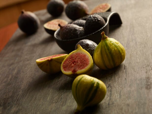 Bunch of fresh figs on a wood table with some cut in half