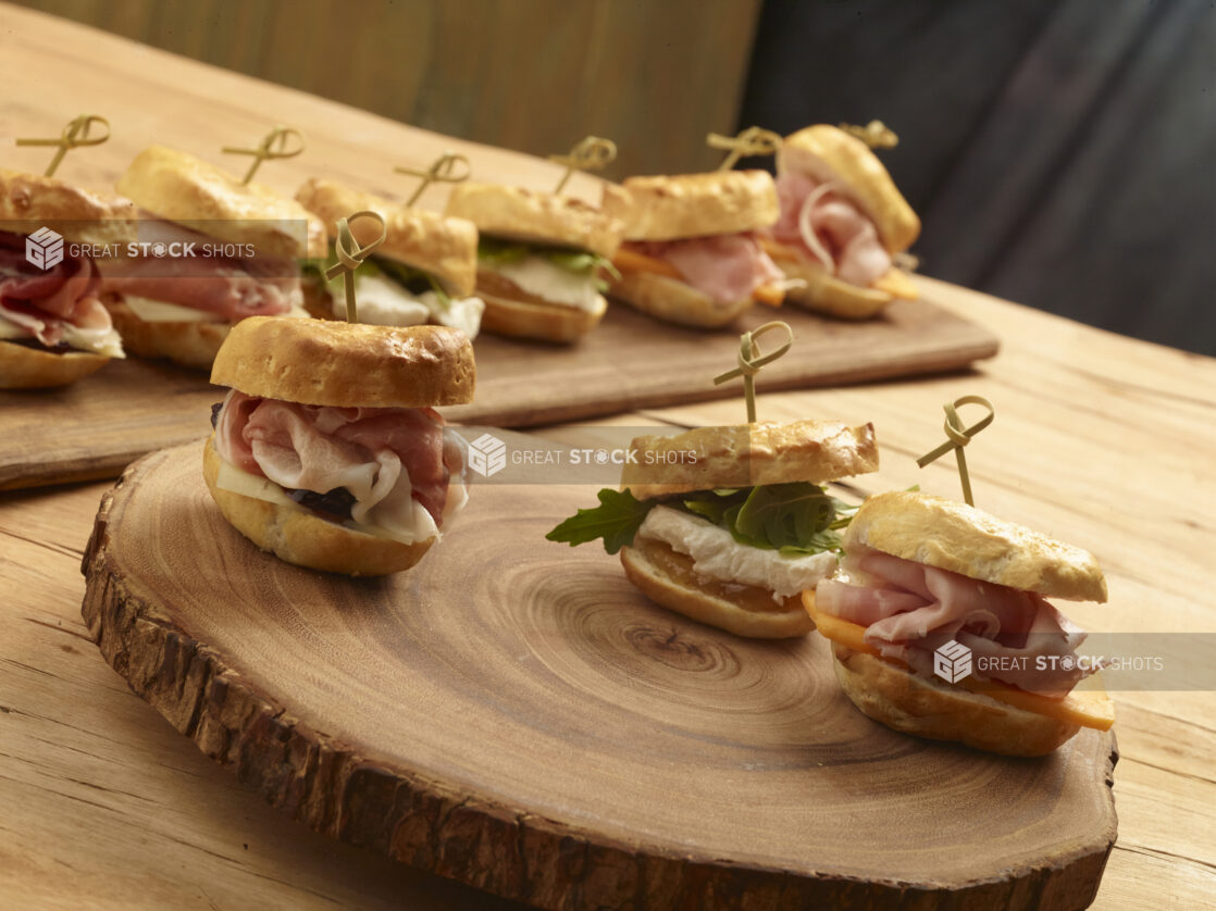 Assorted mini sandwiches with bamboo toothpick on a wooden board