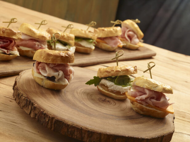 Assorted mini sandwiches with bamboo toothpick on a wooden board