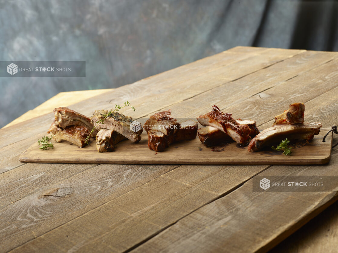 Wooden board of different flavored ribs on a wood table