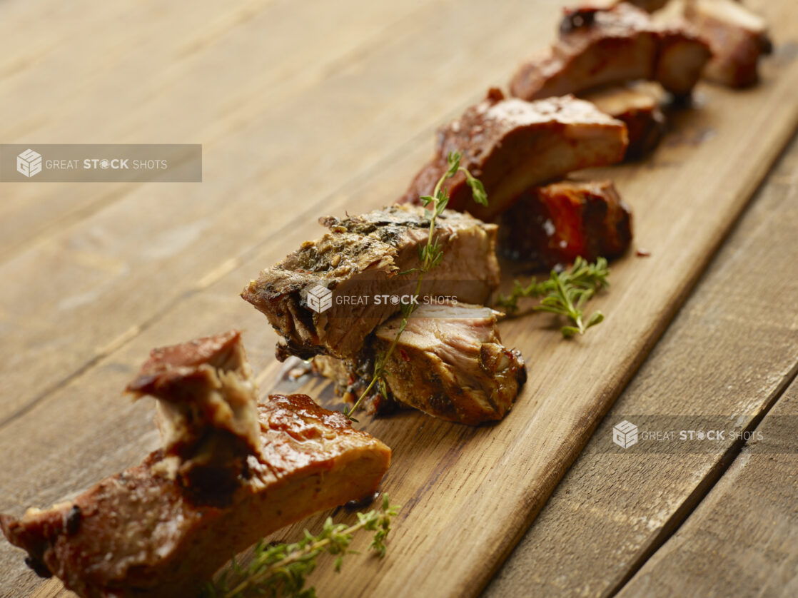 Wooden board of different flavored ribs on a wood table with fresh herbs