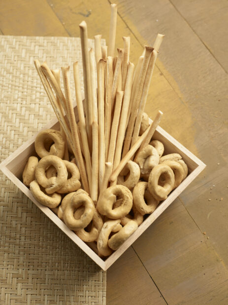 Bread sticks and taralli, italian crackers, in a wood catering box on a wooden background