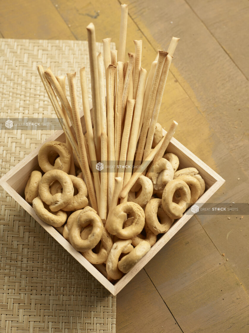 Bread sticks and taralli, italian crackers, in a wood catering box on a wooden background