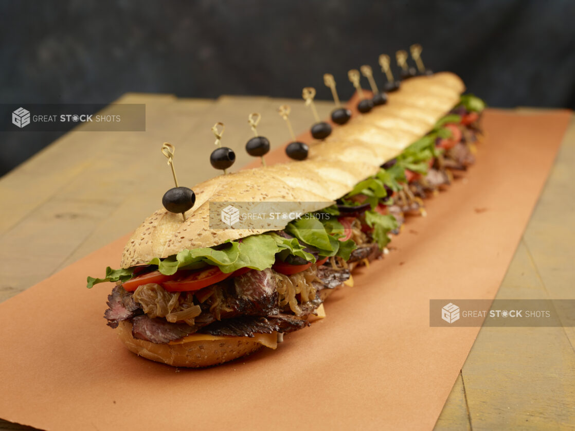 Giant submarine sandwich with roast beef, caramelized onions, tomatoes, lettuce and cheese