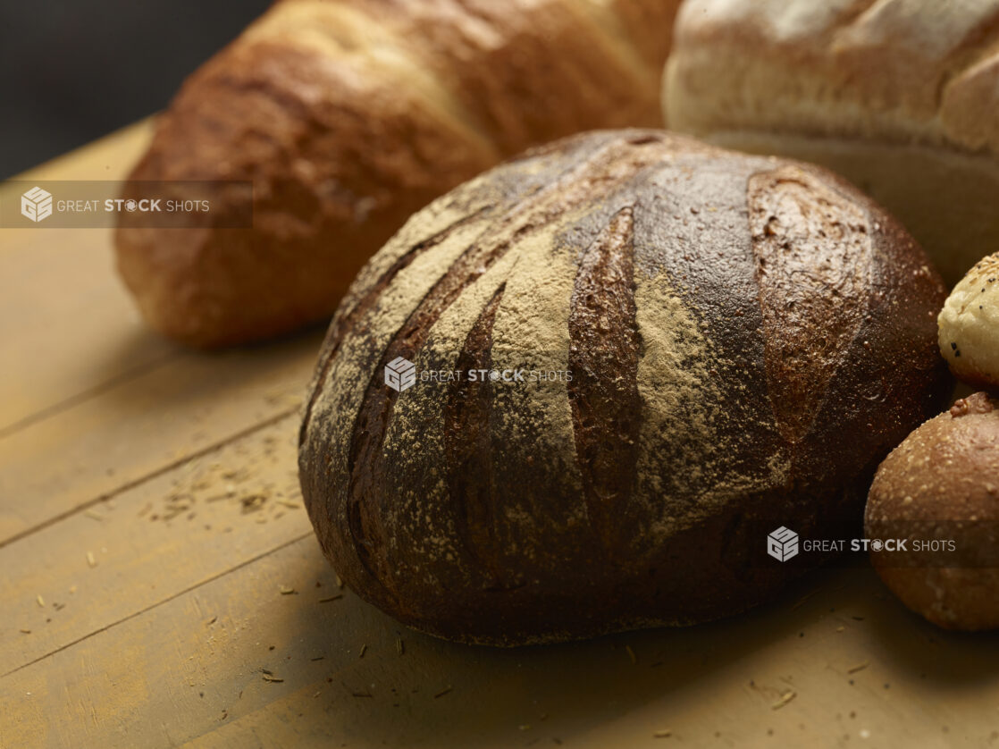 Assorted whole rustic baked breads on a wooden background