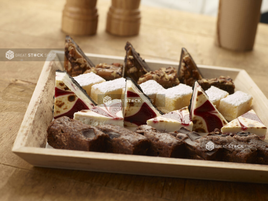 Wood catering tray of assorted desserts on a wood table