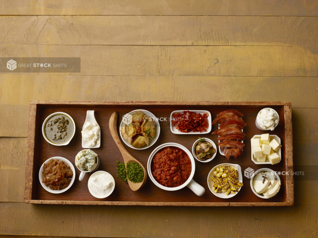 Large wood tray of toppings for a meal on a wood table