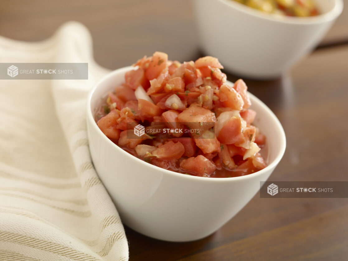 Small white bowl of bruschetta on a wood table