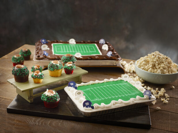 Two football themed cakes with football field and sprinkle cupcakes with edible footballs and a bowl of popcorn for a themed party