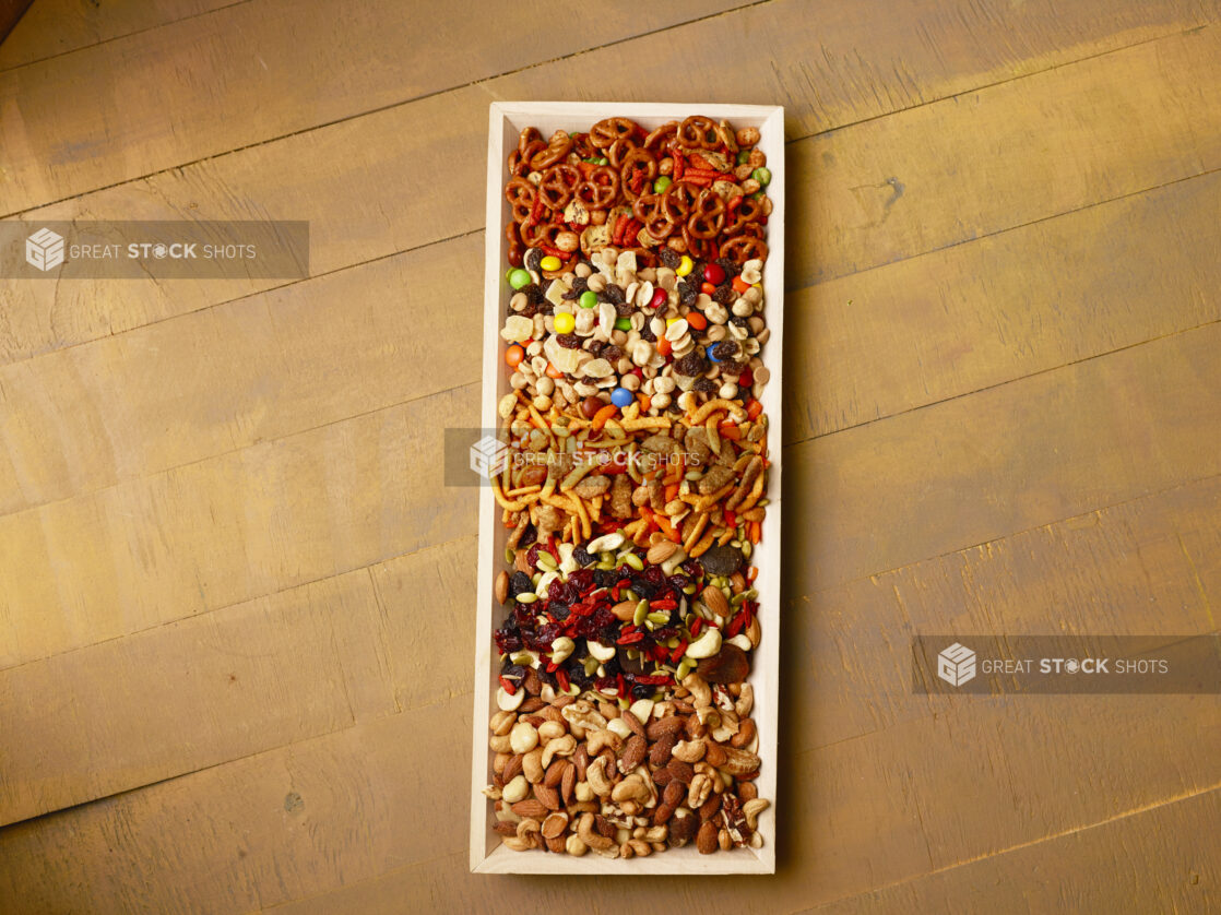 Overhead view of a wood tray filled with snacks on a wood table