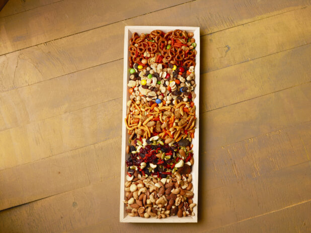 Overhead view of a wood tray filled with snacks on a wood table