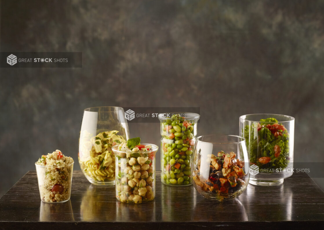 Assortment vegetarian salads in different glass containers on a wood table