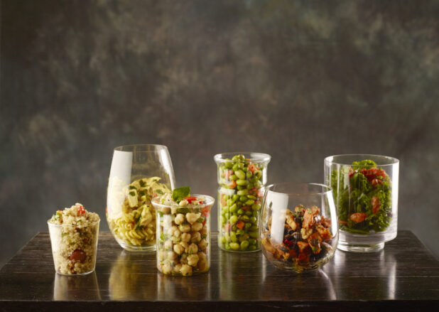Assortment vegetarian salads in different glass containers on a wood table