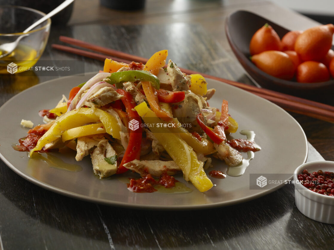 Plate of chicken fajitas sticked high and drizzled in chili oil on a wood table