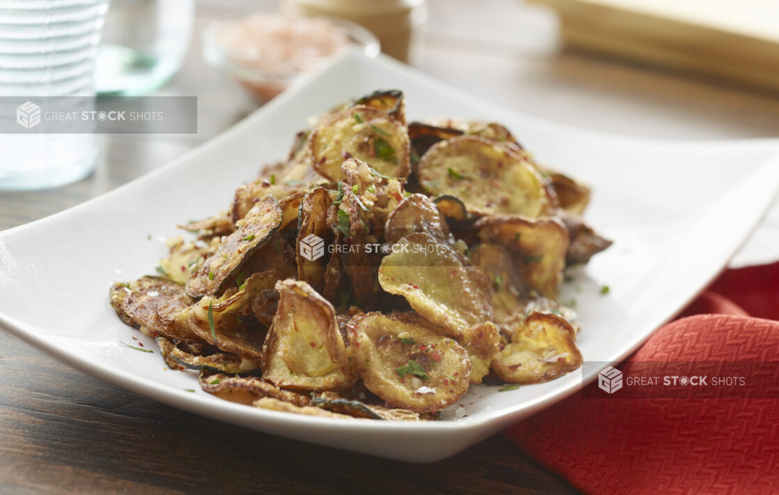 White bowl of fried vegetable chips on a wood table