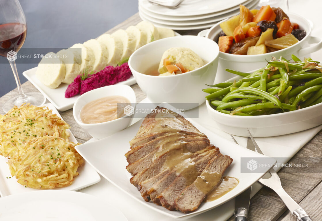 Selection of traditional Jewish dishes on a white table cloth on a wood table