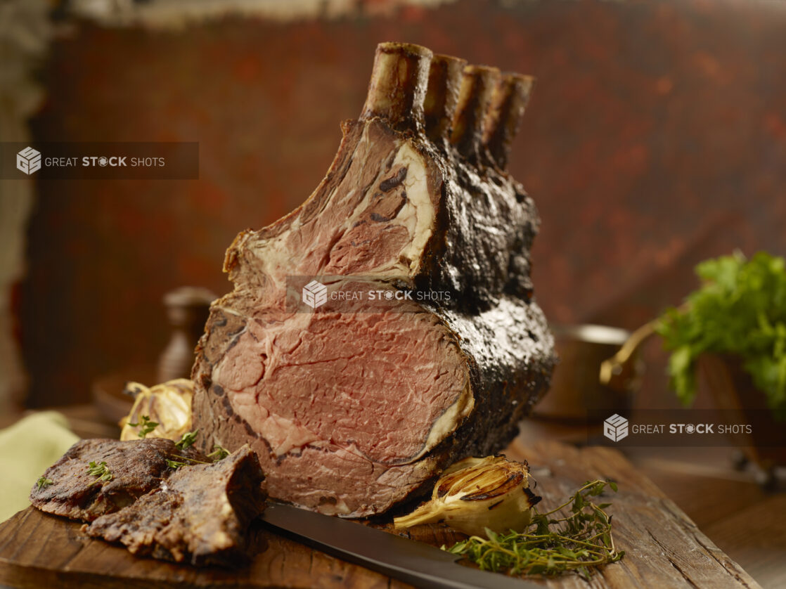 Standing rib roast cooked medium rare with roasted garlic on a butchers block