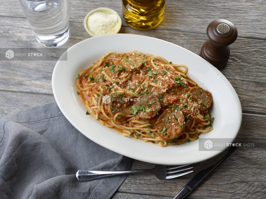 Overhead of white plate of spaghetti and meatballs with grated parmesan and parsley on top