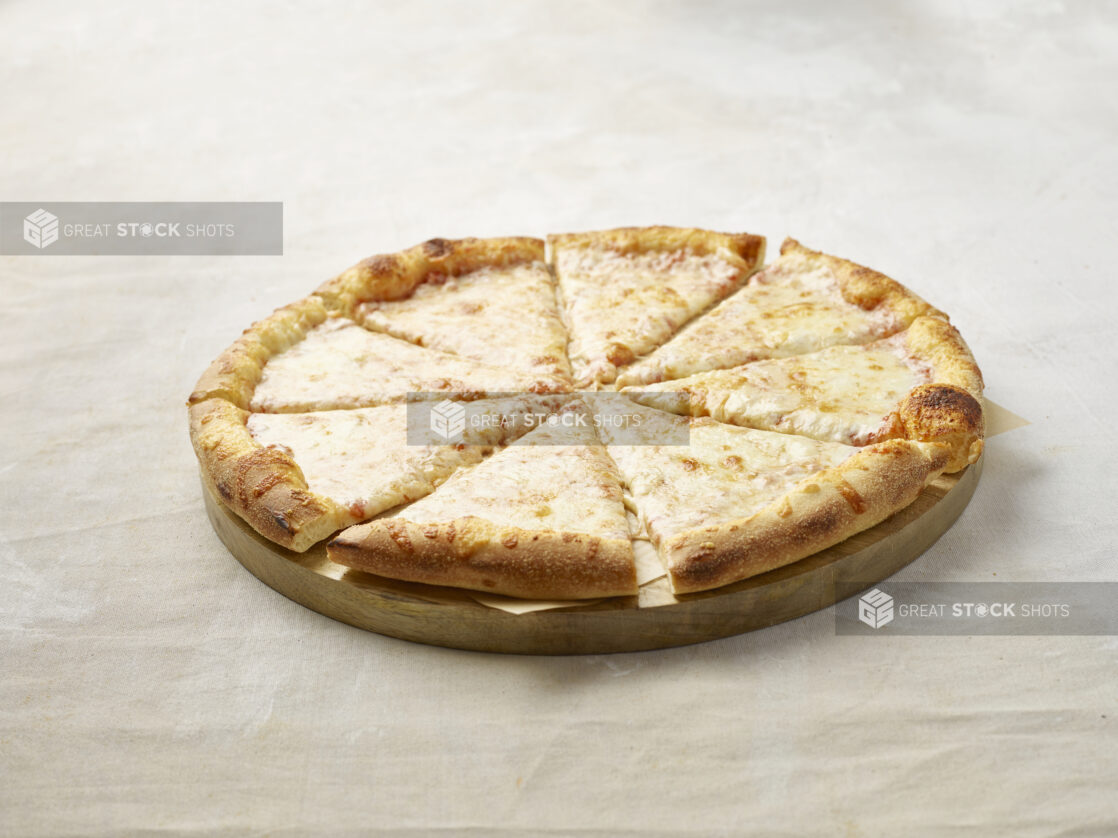 Sliced cheese pizza on a wooden board with parchment paper