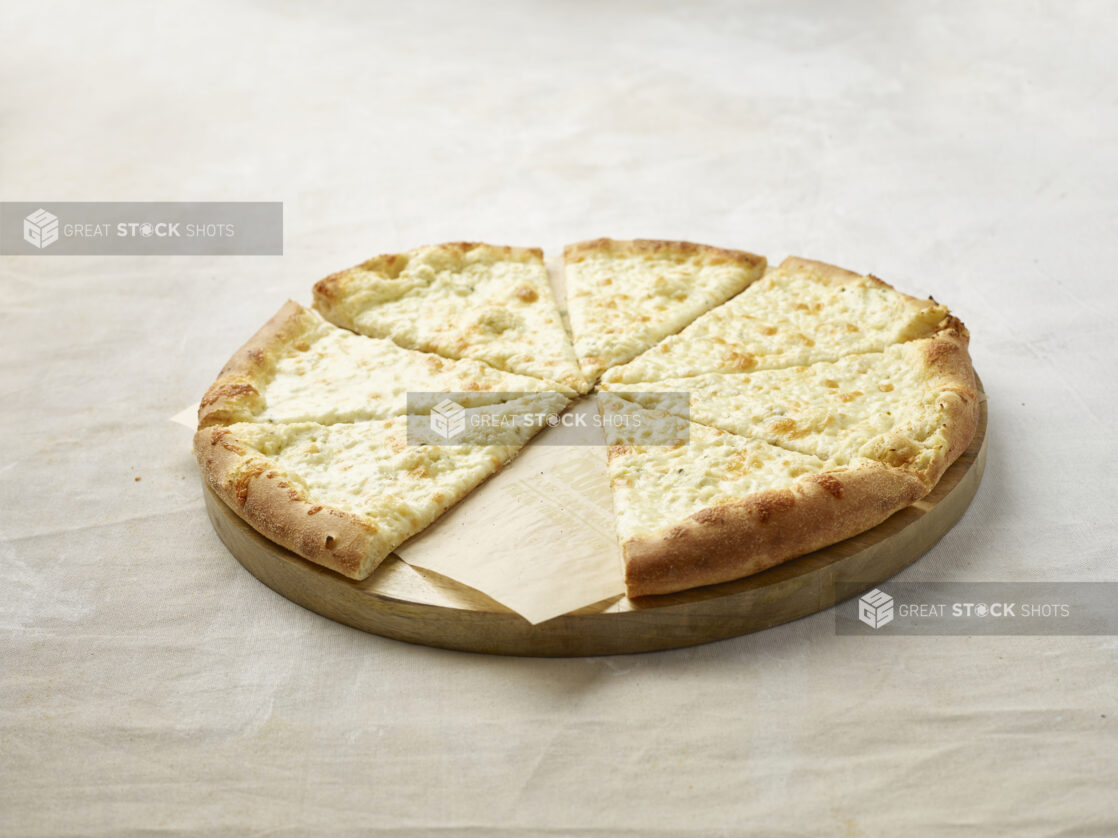 Sliced cheese only pizza with a slice missing on a wooden board with parchment paper