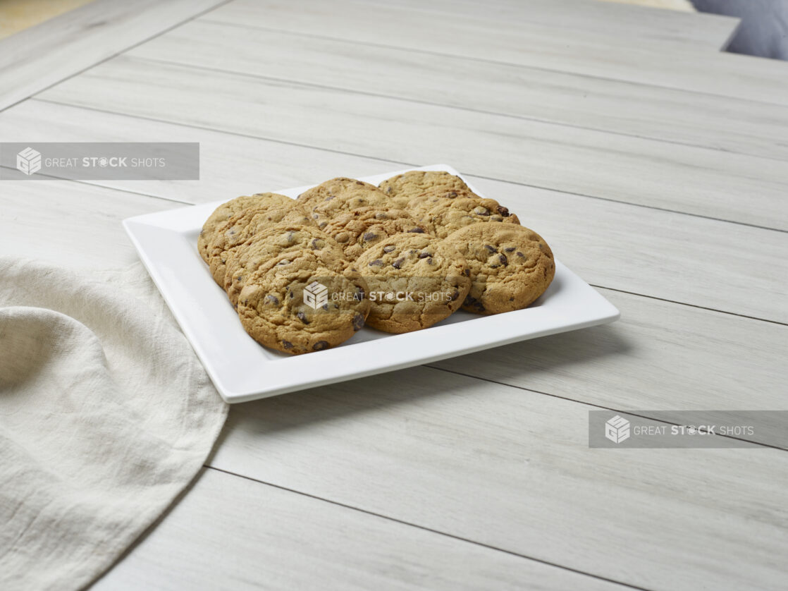 Plate of a dozen chocolate chip cookies on a light wooden background