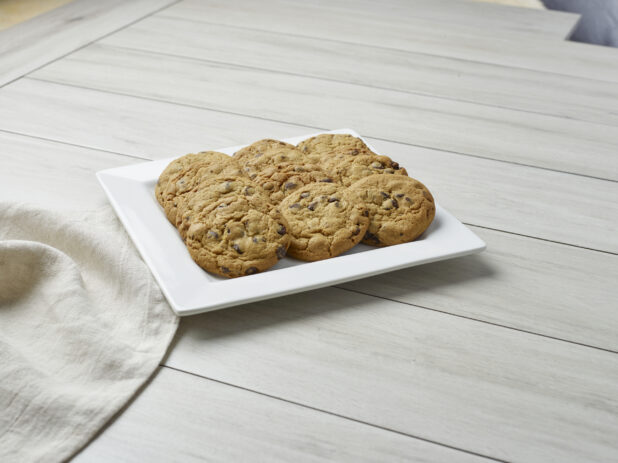 Plate of a dozen chocolate chip cookies on a light wooden background