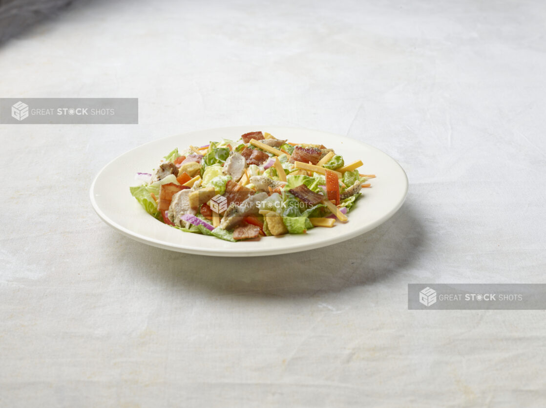 Bowl of chicken bacon garden salad on a light background