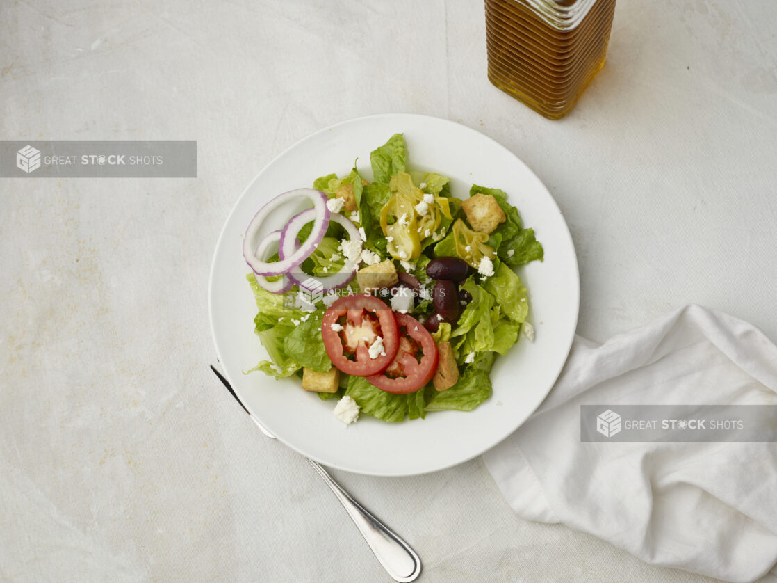 Overhead view of Greek salad with napkin on a white table cloth