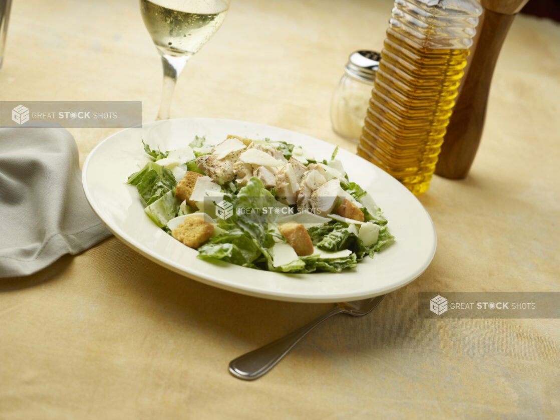 Caesar salad with a glass of white wine on a beige background