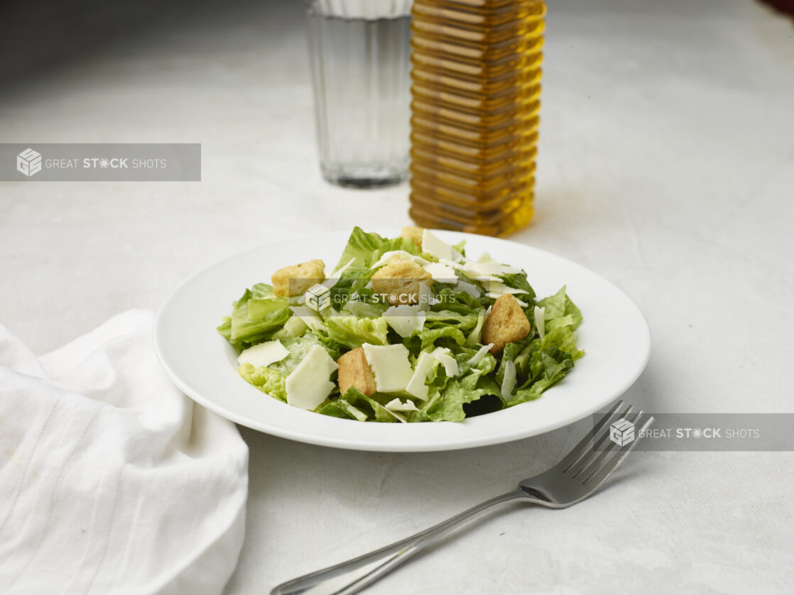 Caesar salad with white napkin on a white table cloth