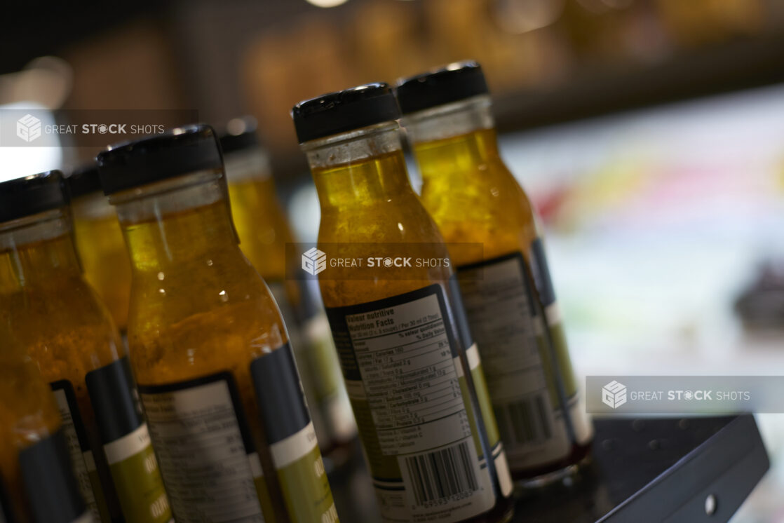 Close Up of Bottles of Olive Oil and Balsamic Vinegar Dressing Showing the Nutrition Label on a Shelf in a Gourmet Grocery Store Setting