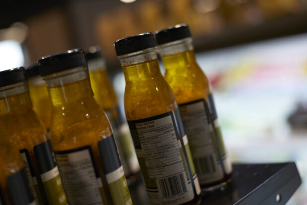 Close Up of Bottles of Olive Oil and Balsamic Vinegar Dressing Showing the Nutrition Label on a Shelf in a Gourmet Grocery Store Setting