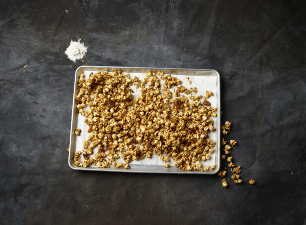 Caramel candied popcorn on a silver baking tray lined with parchment