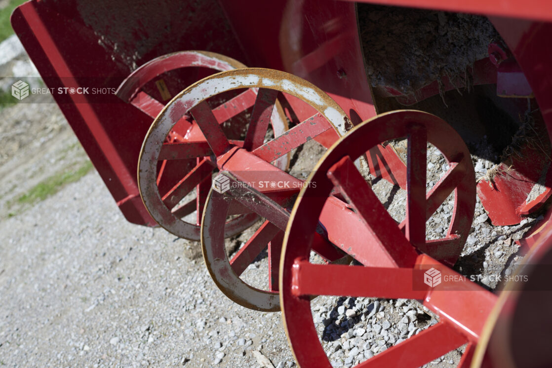 Close Up of a Red Painted Metal Snowblower in an Outdoor Farm Setting