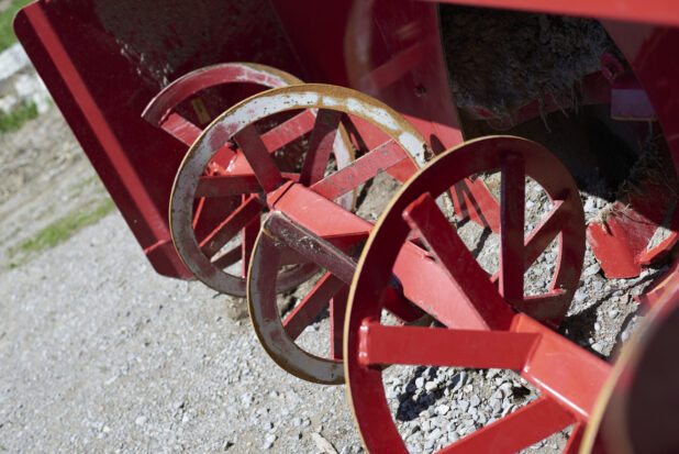 Close Up of a Red Painted Metal Snowblower in an Outdoor Farm Setting