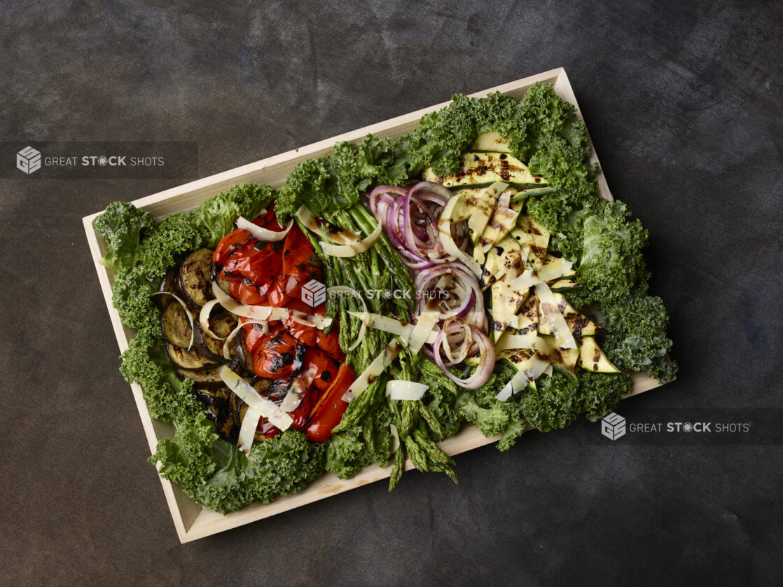 Over head of grilled vegetable platter in a wooden tray on a dark background