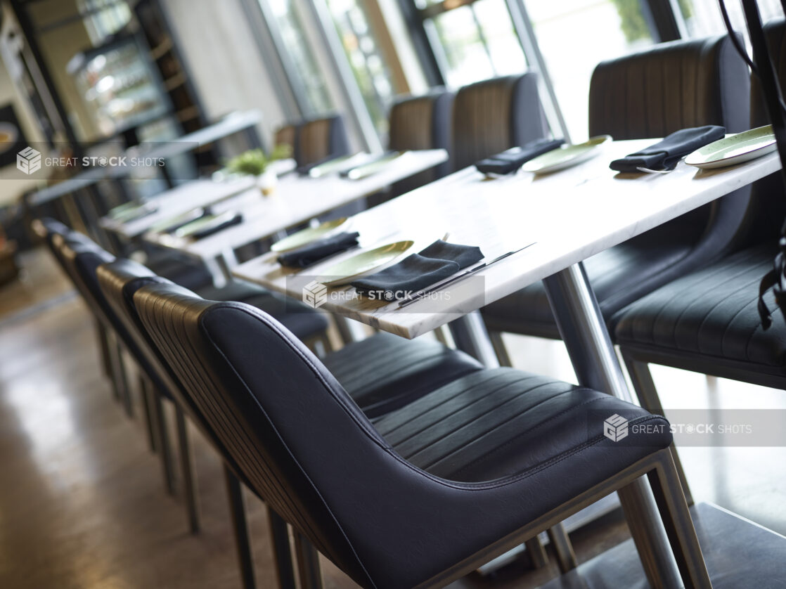 Interior of a fine dining restaurant with white marble tops and black leather seating