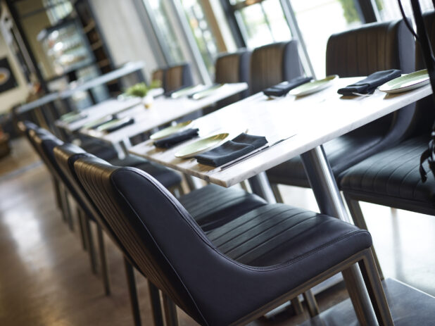 Interior of a fine dining restaurant with white marble tops and black leather seating