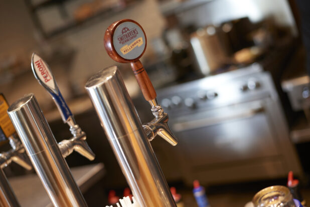 Beer taps with kitchen range in background, close-up, tilted angle