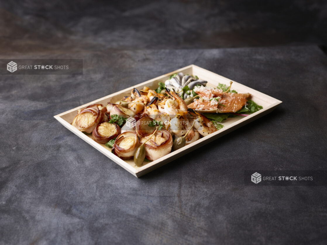 Seafood platter on a wooden tray with a dark background