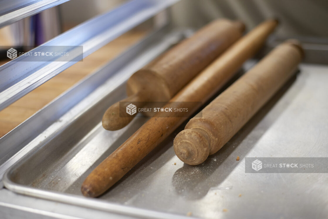 Various wooden rolling pins on an aluminum sheet tray, close-up