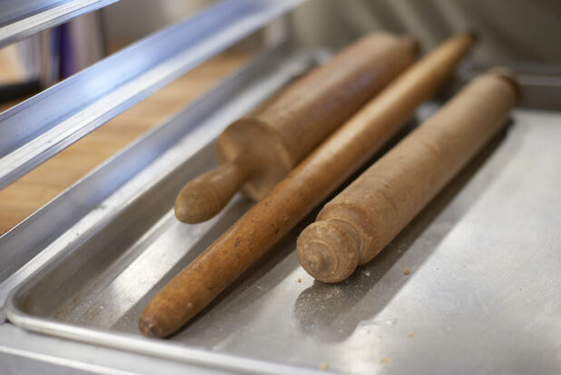 Various wooden rolling pins on an aluminum sheet tray, close-up